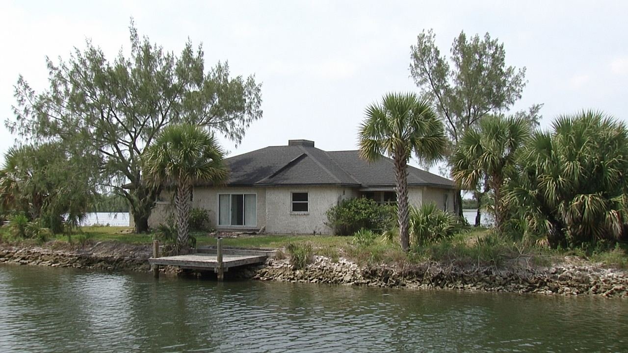 A stucco house on a Brevard canal, with a dock and palms