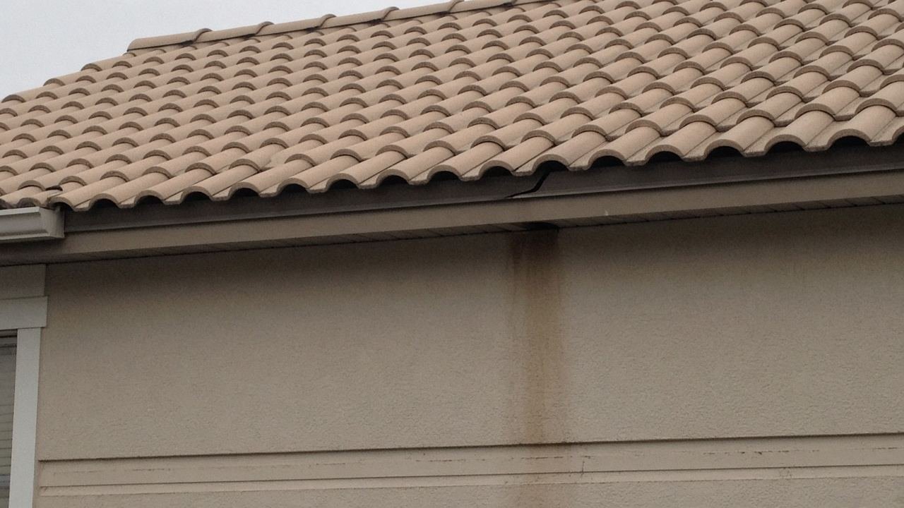 Tile roof with a thin gap at the fascia and a stain on the stucco, shingles still on