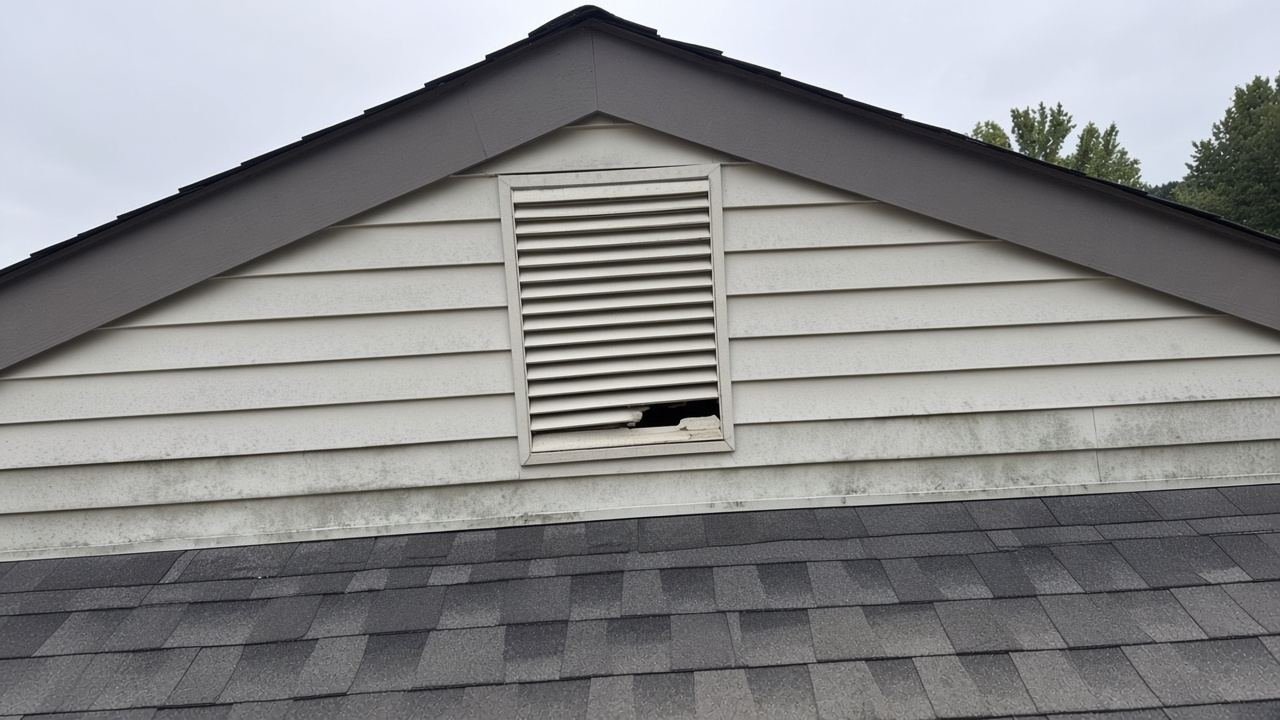 Florida gable vent with a fist-sized hole through the louvers, shingles still on
